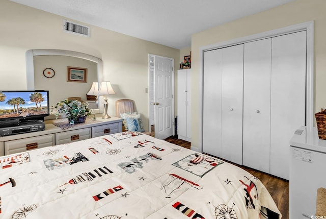 bedroom with a closet, visible vents, and dark wood-type flooring