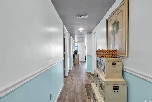 hallway with visible vents, baseboards, and wood finished floors