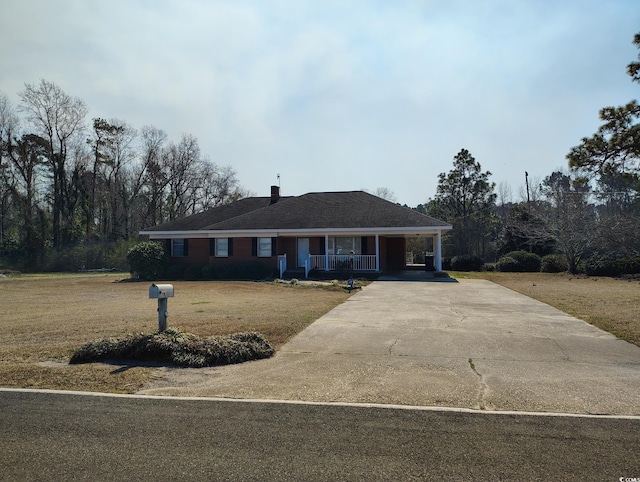 view of front of home with an attached carport, a porch, concrete driveway, and a front yard