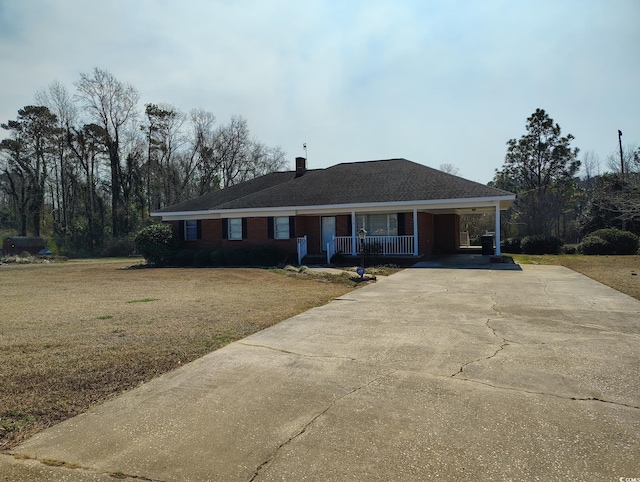 ranch-style home featuring a front lawn, a porch, a chimney, a carport, and driveway