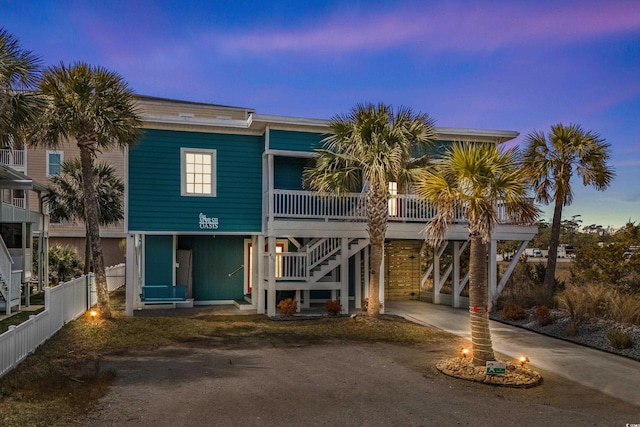 view of front of property with stairs, fence, and dirt driveway