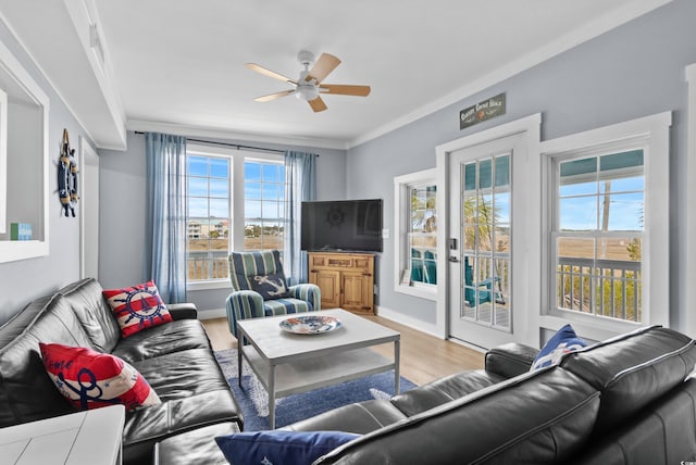 living room with a ceiling fan, wood finished floors, baseboards, and ornamental molding