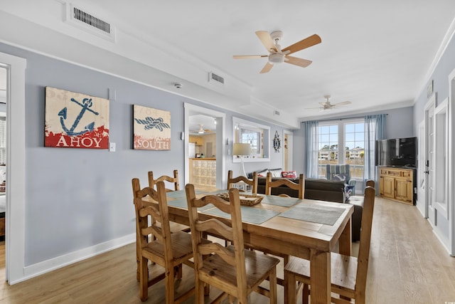 dining room with crown molding, baseboards, visible vents, and light wood finished floors