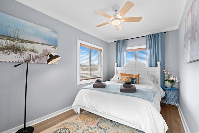 bedroom with a ceiling fan, crown molding, baseboards, and wood finished floors