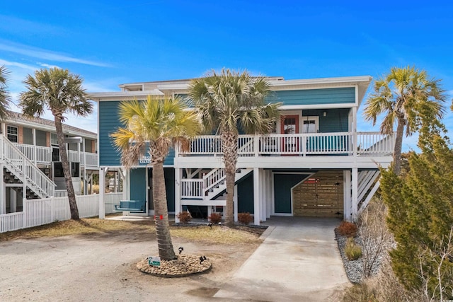 view of front of home with stairway, covered porch, and concrete driveway