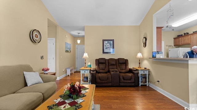 living area featuring baseboards, lofted ceiling, and wood finished floors