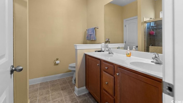 bathroom with double vanity, baseboards, a stall shower, and a sink