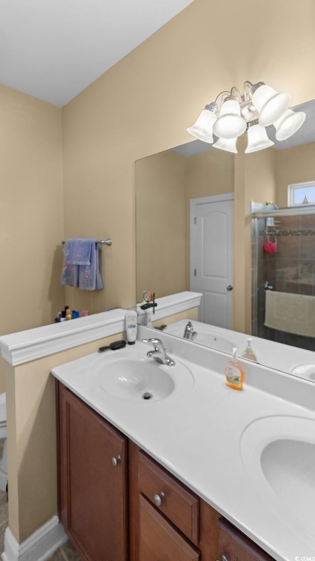 full bathroom featuring double vanity, a shower stall, toilet, and a sink