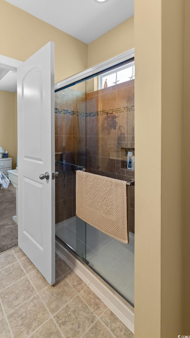 bathroom with a shower with door and tile patterned floors