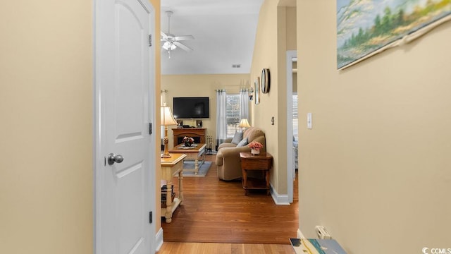 corridor with visible vents, wood finished floors, and baseboards