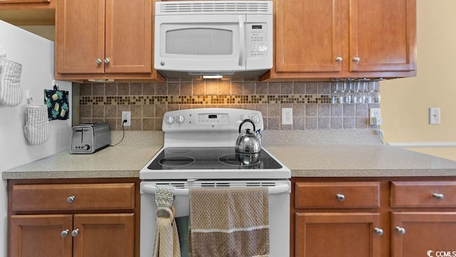 kitchen with brown cabinetry, decorative backsplash, white appliances, and light countertops