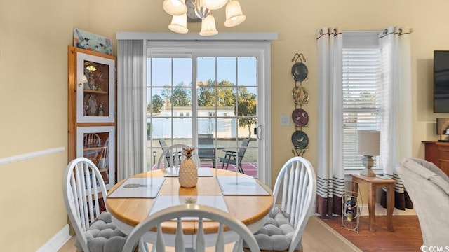 dining room featuring baseboards, a notable chandelier, a healthy amount of sunlight, and wood finished floors