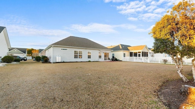 rear view of property with a lawn and fence