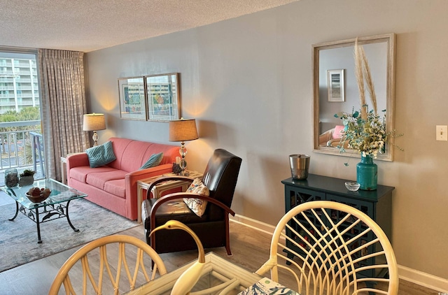 living room with a textured ceiling, baseboards, and wood finished floors