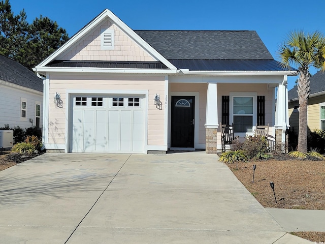 view of front of property featuring driveway, a standing seam roof, covered porch, metal roof, and a garage