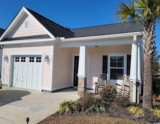 view of front of house featuring concrete driveway, covered porch, metal roof, a garage, and a standing seam roof