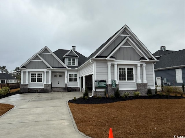 craftsman inspired home featuring a garage, brick siding, board and batten siding, and driveway