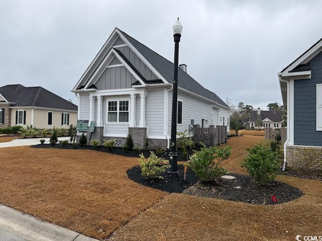 view of front of home with a front lawn, brick siding, and board and batten siding