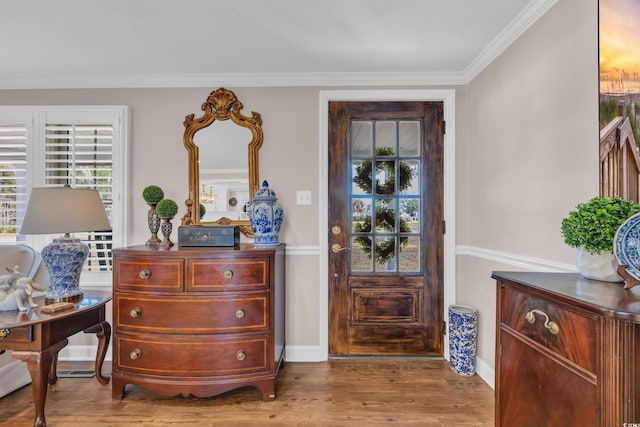 entryway featuring wood finished floors, baseboards, and ornamental molding