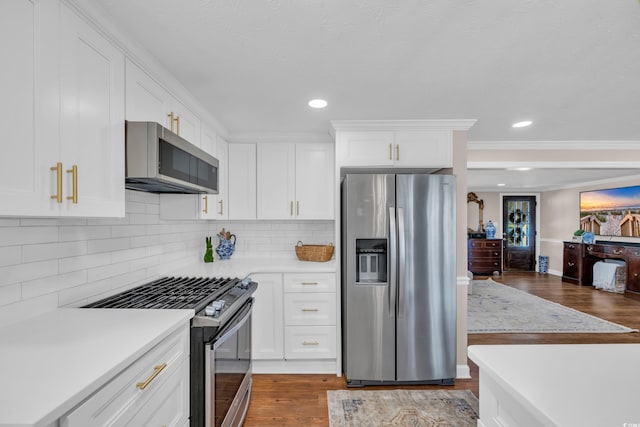 kitchen featuring tasteful backsplash, wood finished floors, appliances with stainless steel finishes, white cabinets, and light countertops