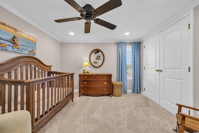 bedroom with a nursery area, carpet, ceiling fan, and crown molding