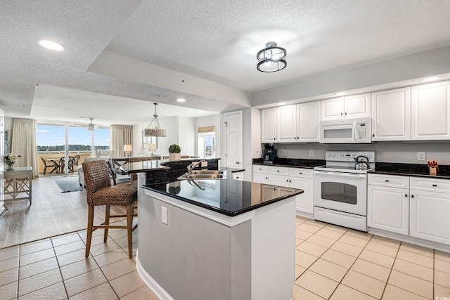 kitchen featuring white appliances, light tile patterned floors, a sink, white cabinetry, and dark countertops