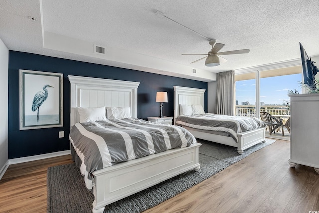 bedroom featuring access to exterior, visible vents, ceiling fan, baseboards, and wood finished floors