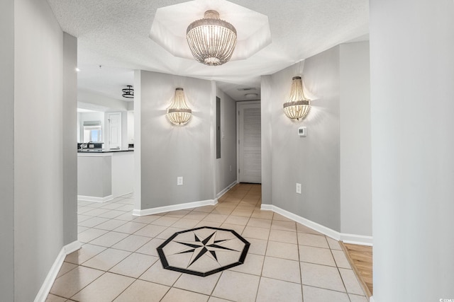 interior space with light tile patterned floors, a notable chandelier, a textured ceiling, and baseboards