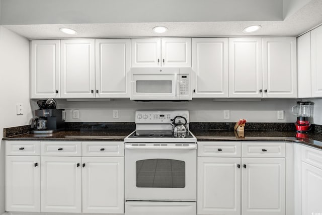 kitchen featuring white appliances, dark stone countertops, recessed lighting, white cabinets, and a textured ceiling