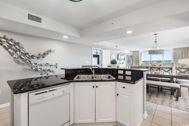 kitchen with light tile patterned floors, visible vents, white dishwasher, a sink, and white cabinetry