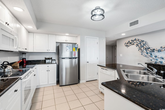 kitchen featuring white appliances, light tile patterned floors, visible vents, a sink, and white cabinetry