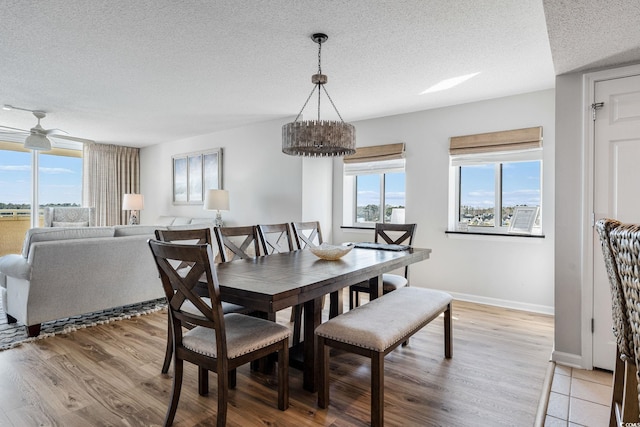 dining space featuring ceiling fan, baseboards, light wood-type flooring, and a textured ceiling