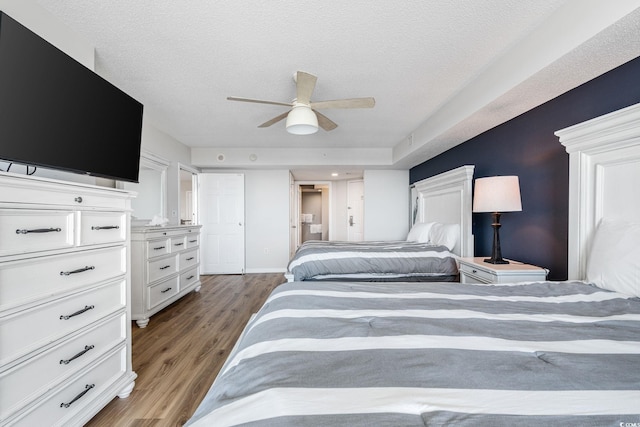 bedroom featuring ceiling fan, wood finished floors, baseboards, and a textured ceiling