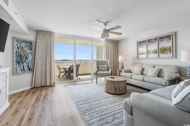 living room with visible vents, baseboards, a textured ceiling, and wood finished floors