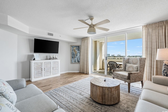 living area with visible vents, a textured ceiling, and wood finished floors