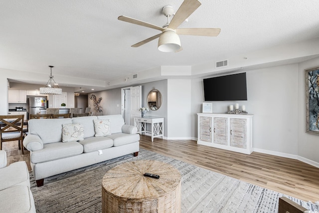 living room with visible vents, baseboards, and wood finished floors