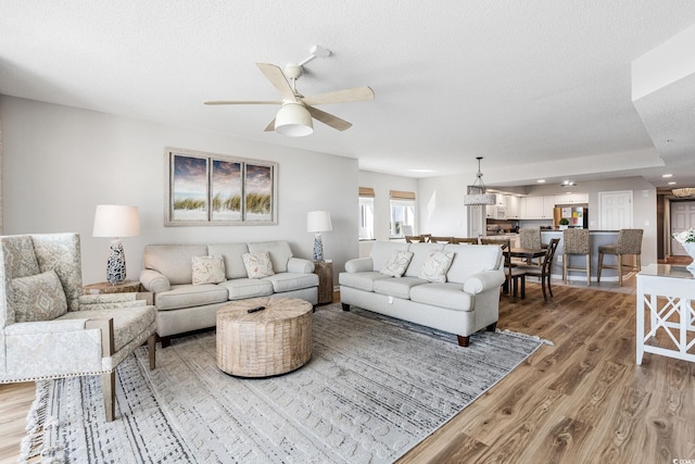 living area featuring a textured ceiling, light wood-style floors, and a ceiling fan