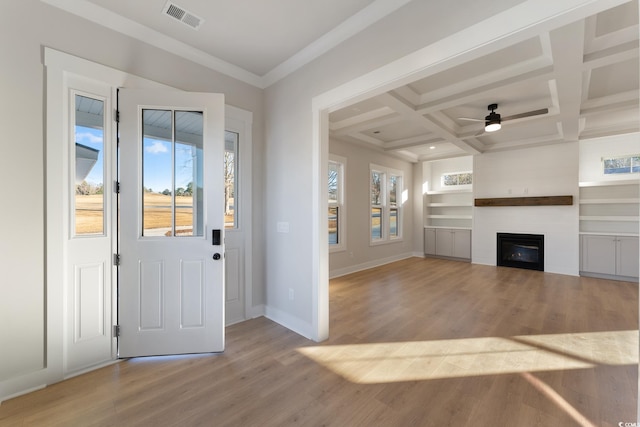 foyer featuring visible vents, baseboards, light wood-style flooring, a glass covered fireplace, and coffered ceiling