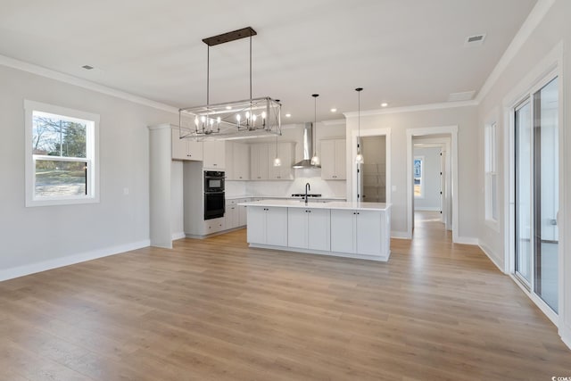 kitchen with ornamental molding, dobule oven black, a sink, wall chimney range hood, and light countertops