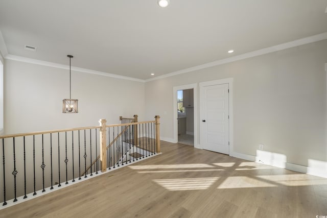 empty room featuring visible vents, ornamental molding, baseboards, and wood finished floors