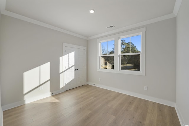 unfurnished room with wood finished floors, baseboards, and ornamental molding