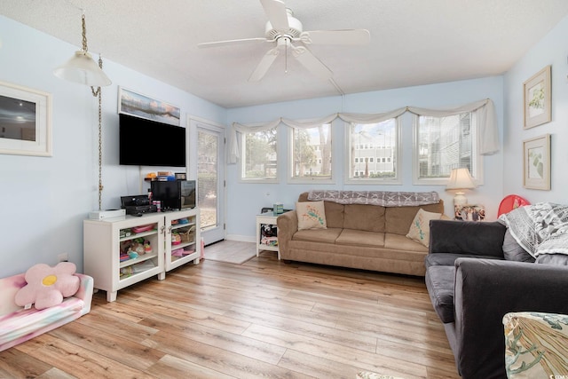 living area with ceiling fan, light wood-style flooring, and a textured ceiling