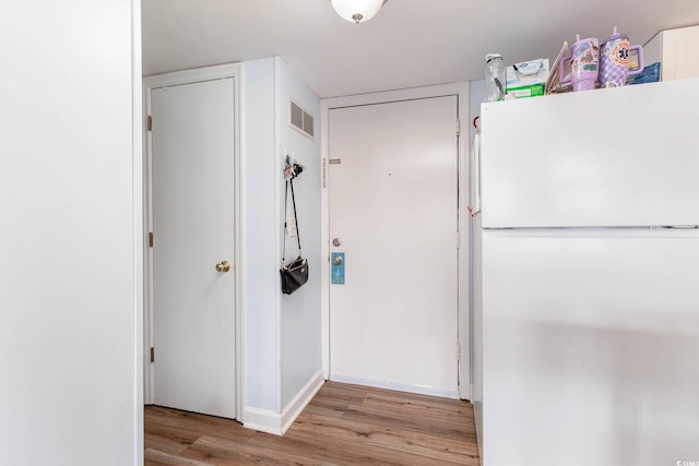 corridor featuring light wood-style floors and baseboards