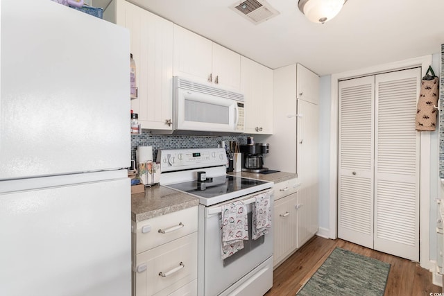 kitchen with white appliances, light wood-type flooring, white cabinetry, decorative backsplash, and light countertops