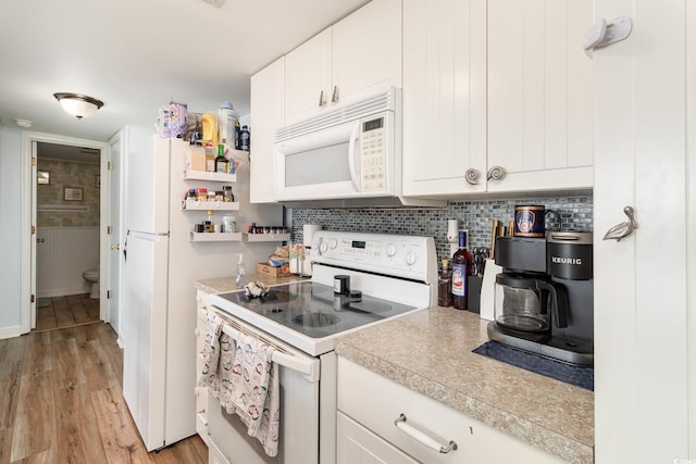 kitchen with white appliances, light countertops, light wood finished floors, tasteful backsplash, and white cabinets