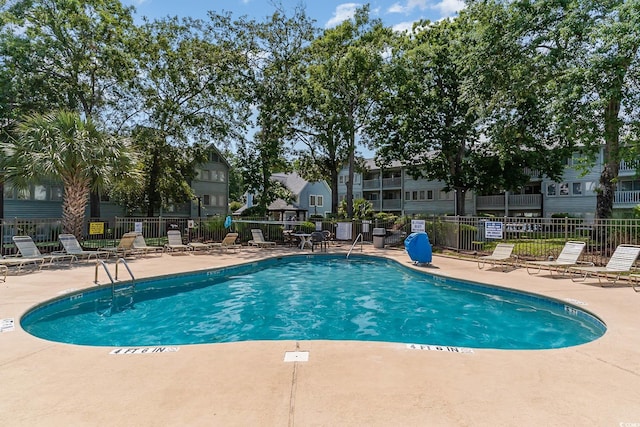 community pool with a patio area and fence