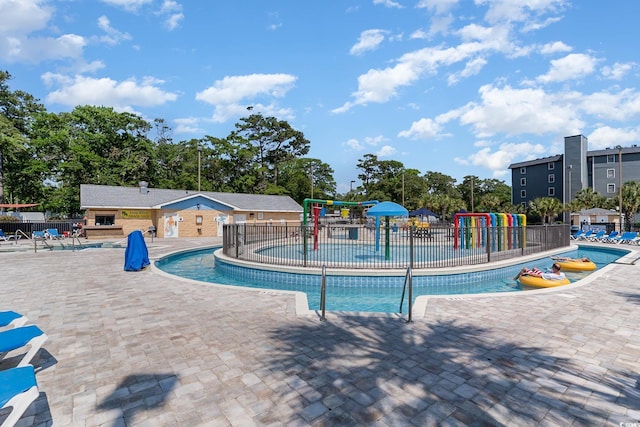 community pool with a water play area, fence, and a patio