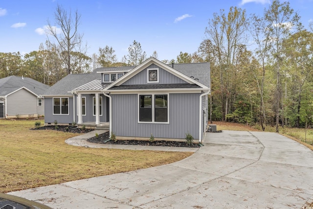 view of front facade featuring concrete driveway, a front lawn, and roof with shingles