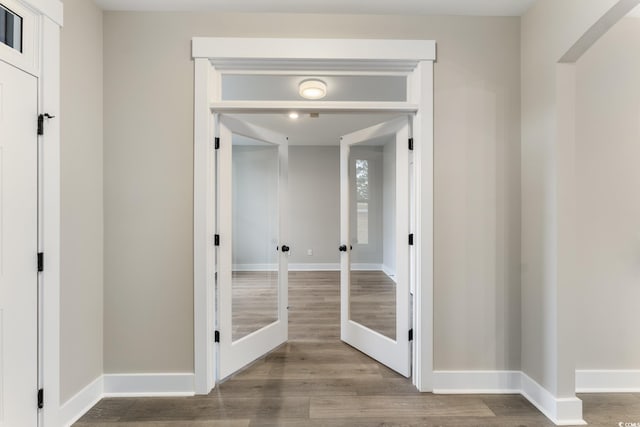 hall featuring french doors, baseboards, and wood finished floors