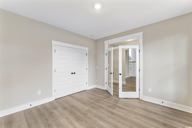 unfurnished bedroom featuring a closet, baseboards, and light wood-style flooring